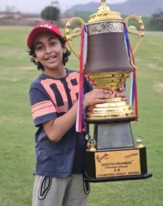   Aarrian Sawant posando com seu troféu depois de vencer o torneio de críquete South Mumbai Premier League