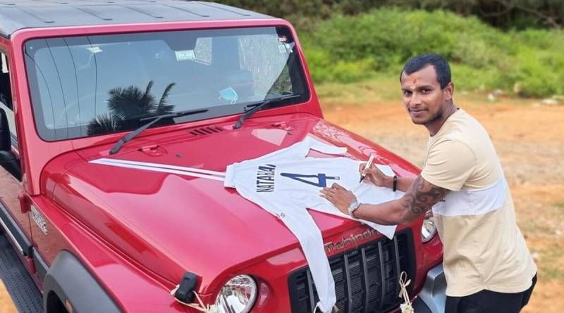 آنند مہندرا کے تحفے میں مہندرا تھر ایس یو وی کے بونٹ پر ٹی نٹراجن اپنے گبا ٹیسٹ جرسی پر دستخط کررہے ہیں