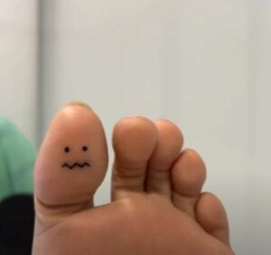   Uma tatuagem de cara mal-humorada no pé direito's thumb